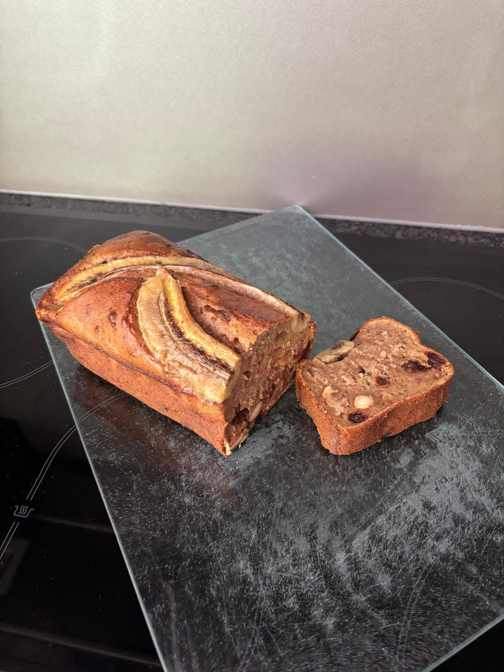 Vers bananenbrood met een plak op een donkere schaal
